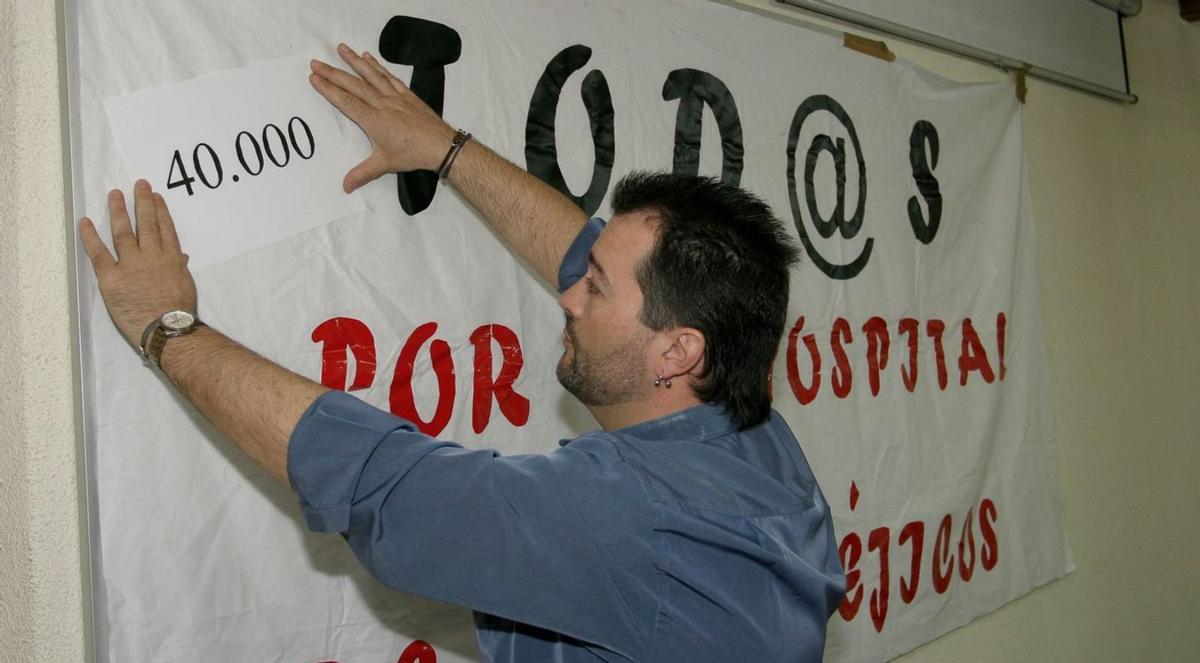 El ahora alcalde de Langreo, entonces párroco de Ciaño, pegando carteles a favor del hospital. | Fernando Rodríguez