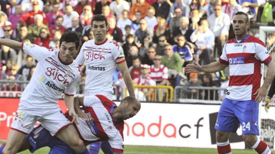 El centrocampista portugués del Sporting de Gijón André Castro (i) se lleva el balón ante el mediocentro del Granada CF Mikel Rico.