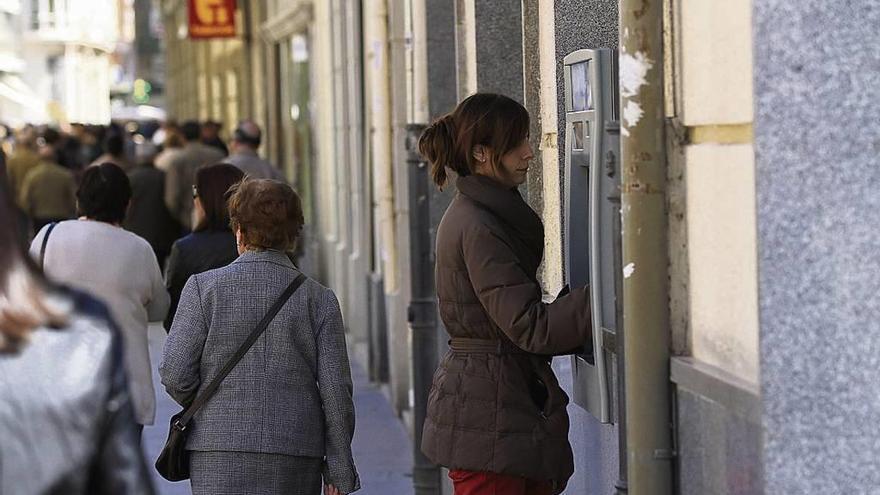 Una mujer saca dinero de un cajero.