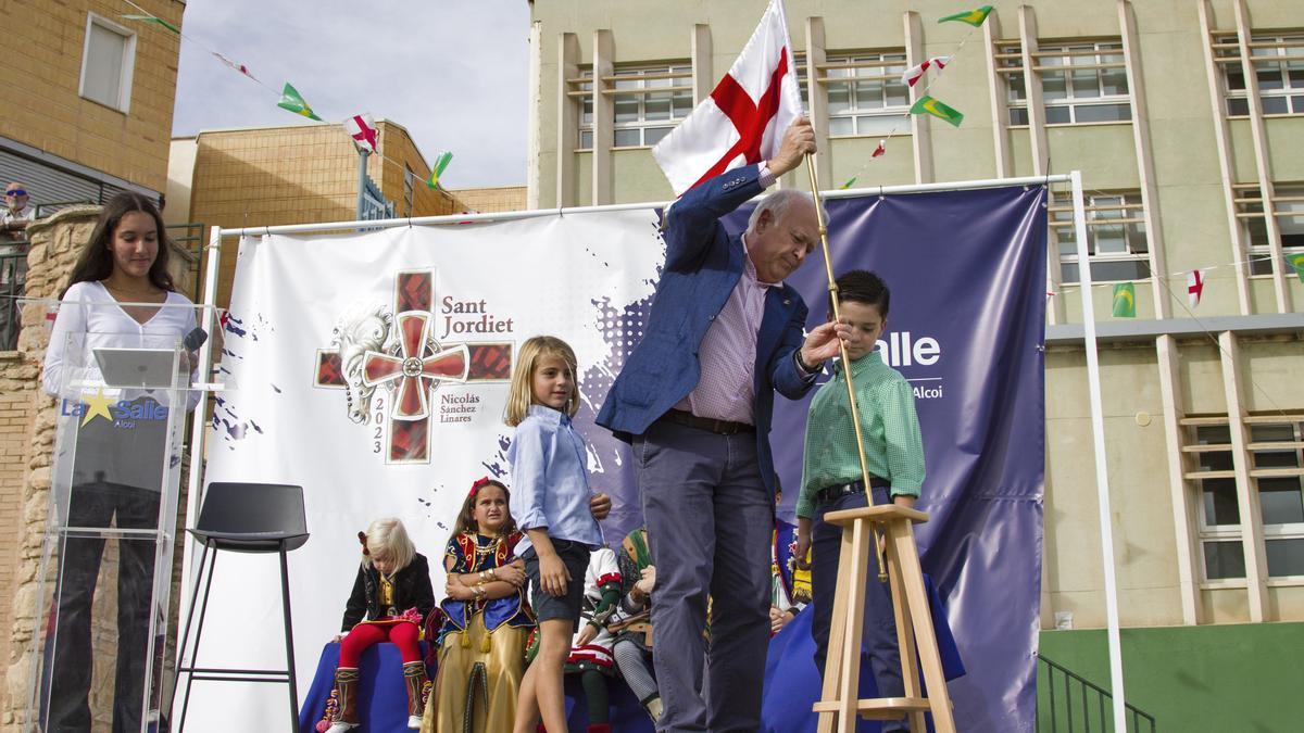 El presidente de la Asociación de San Jorge, Juan José Olcina, recoge la bandera para que el Sant Jordiet saliente se la entregue al nuevo.