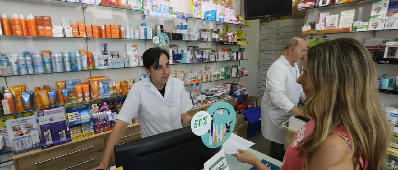 La empleada de una farmacia de València atiende a una clienta, ayer.