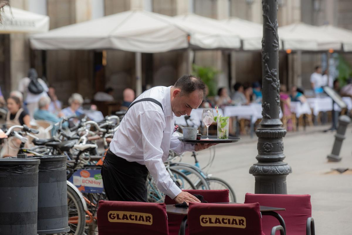 Un camarero limpia una mesa en la plaza Real de Barcelona, a 15 de junio de 2022, en Barcelona, Catalunya (España).
