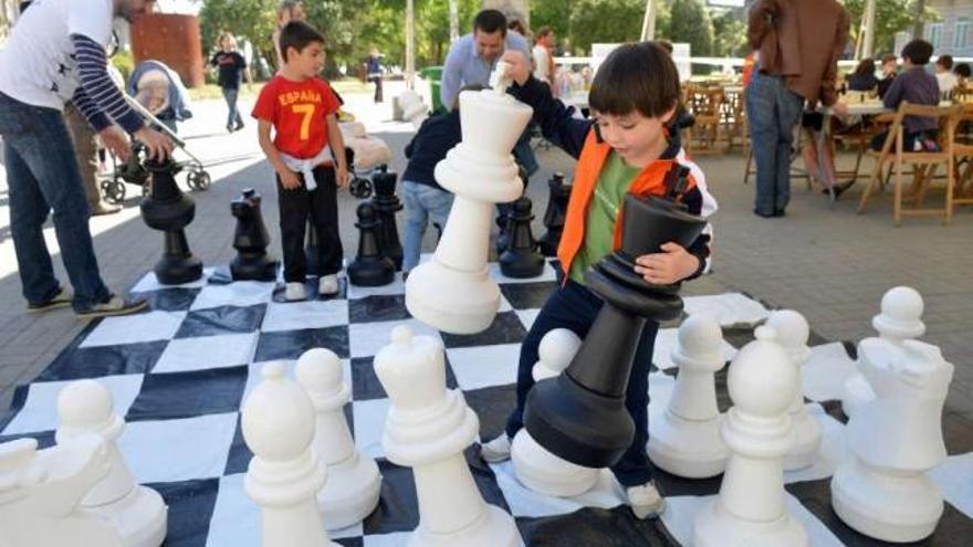 Un niño coloca las piezas en el ajedrez gigante instalado en la plaza de España.  // Rafa Vázquez