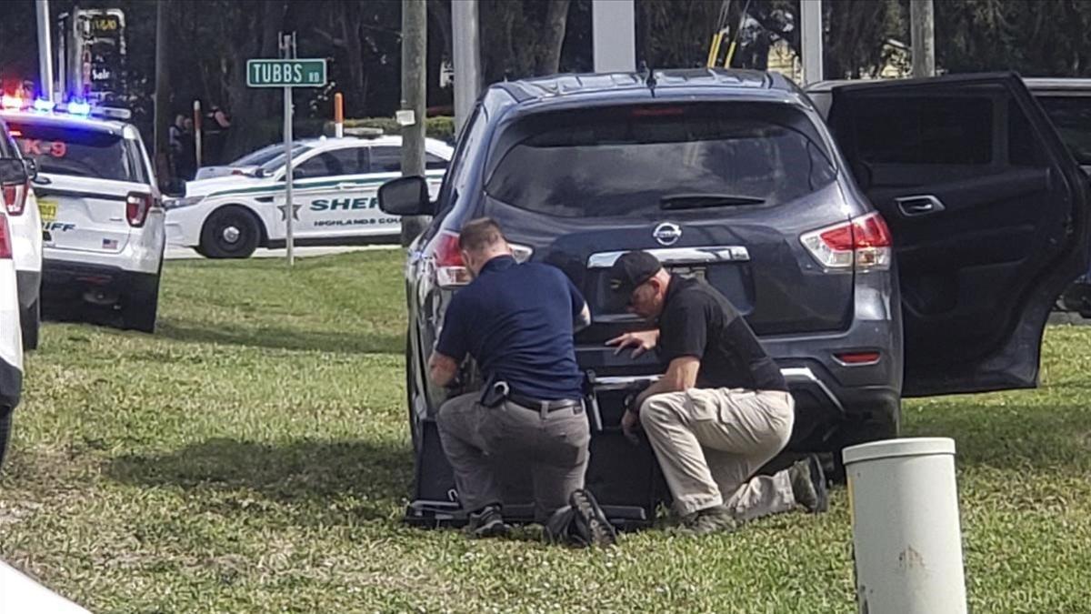 Agentes de policia se protegen tras su vehículo durante el tiroteo en el banco de Florida, el 23 de enero del 2019