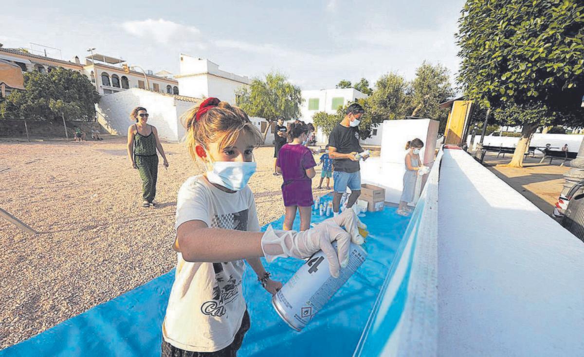 Una niña pinta el mural con su espray. | VICENT MARÍ