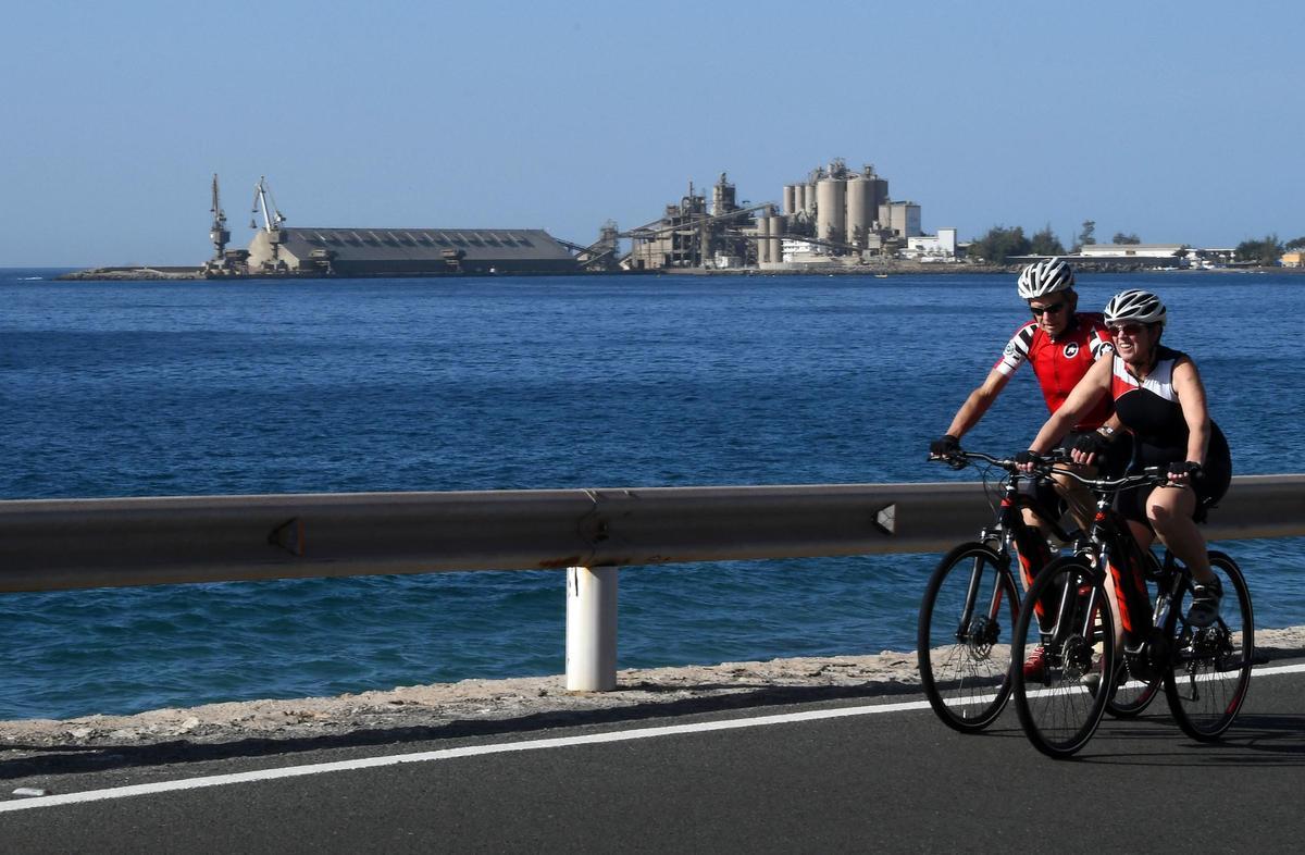 Dos ciclistas con la cementera y el puerto al fondo.