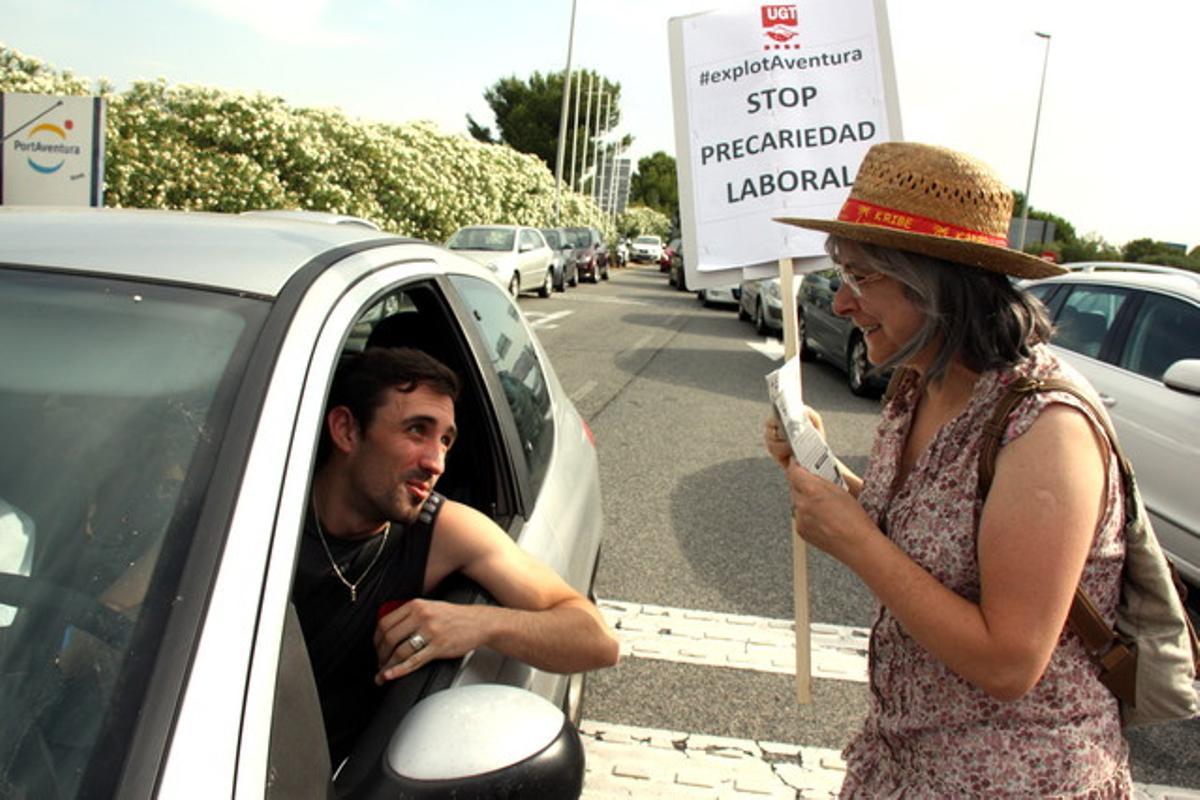 Una treballadora de Port Aventura explica a un visitant els motius de la vaga, aquest matí a l’accés a un pàrquing del parc.