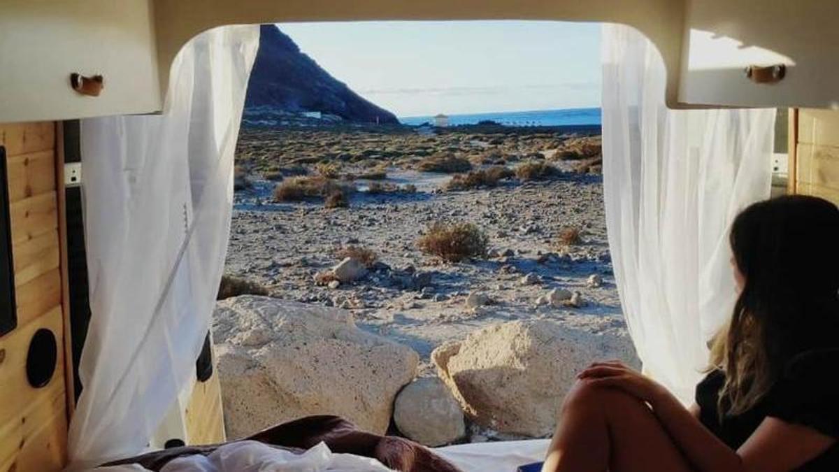 Una joven disfruta de las vistas de una playa desde una caravana.