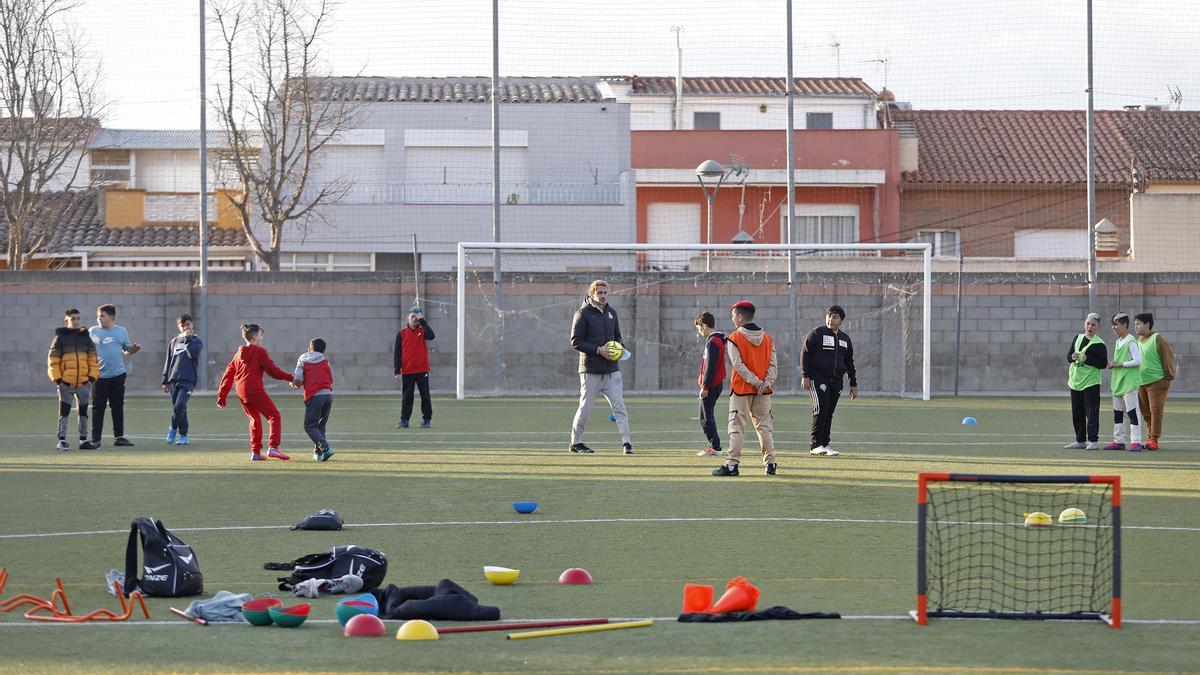 Un entrenador explica un exercici als seus jugadors, una tarda al camp de futbol de Vila-roja.