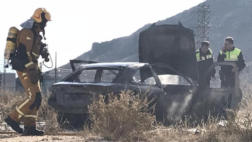 Bomberos y agentes junto al coche quemado