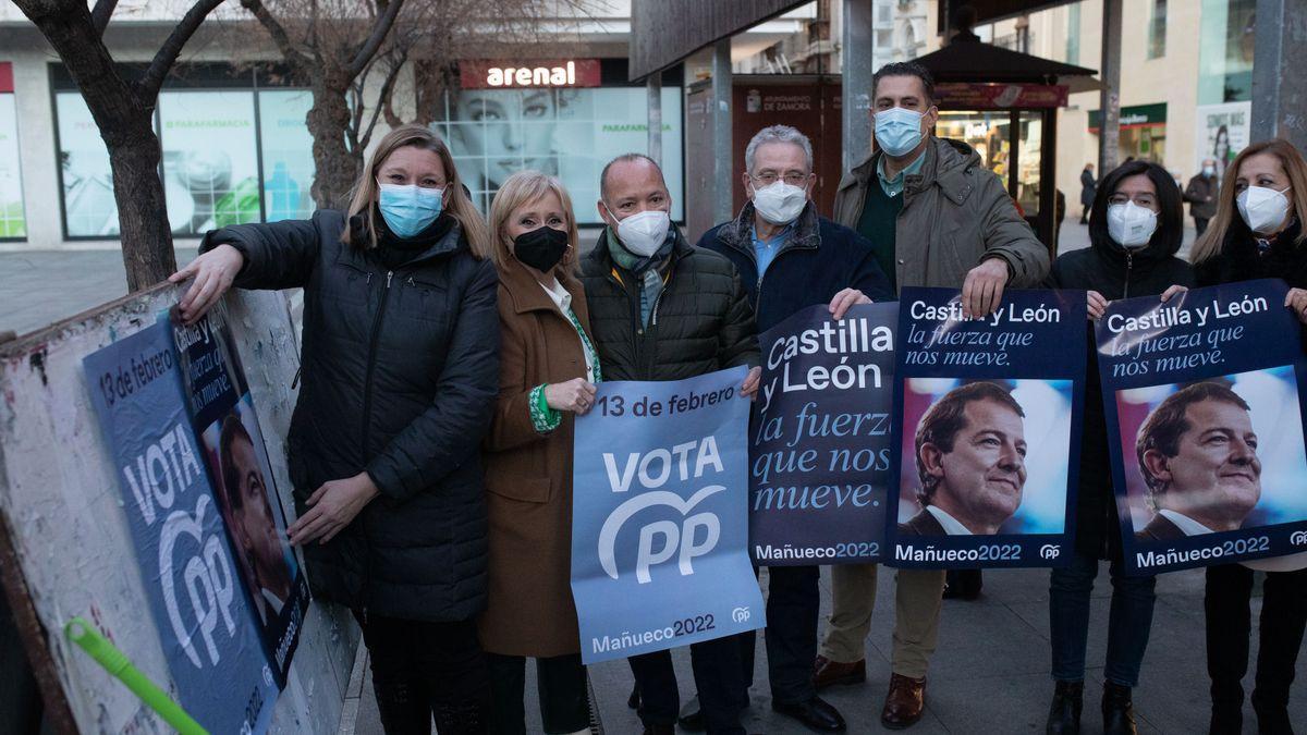 Miembros del PP pegan carteles electorales.
