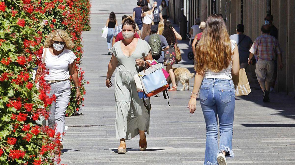 Gente caminando por la calle con mascarilla.