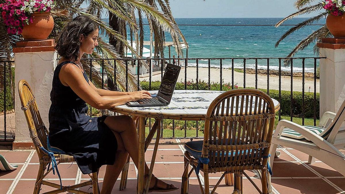 Una mujer teletrabaja desde su casa de la playa.