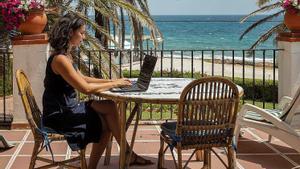 Una mujer teletrabaja desde su casa de la playa.