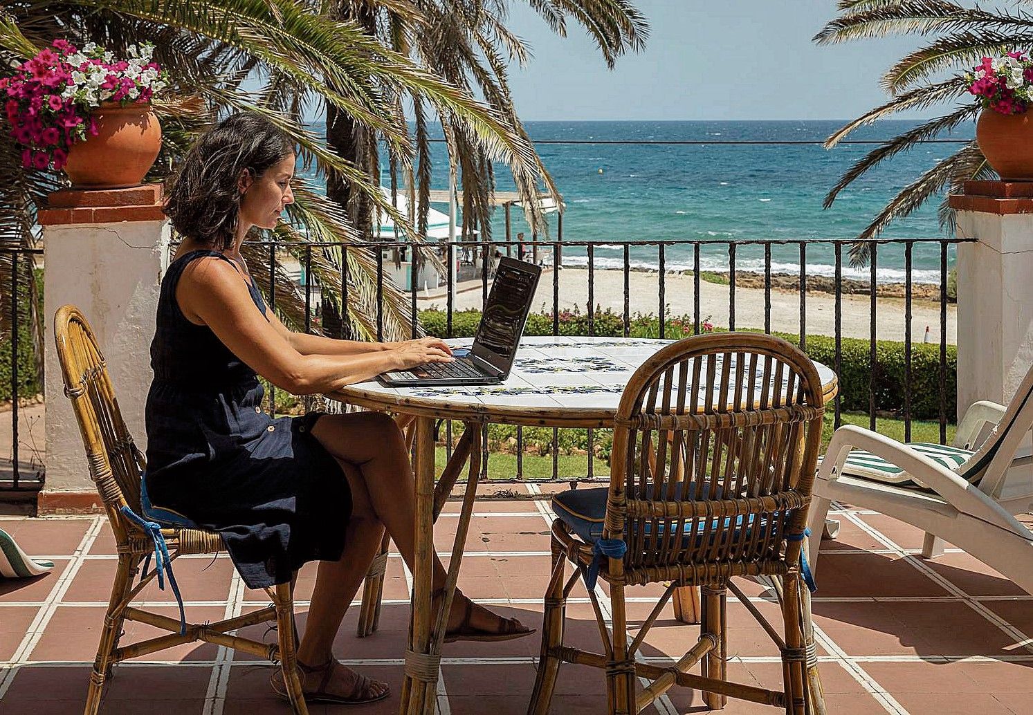 Una mujer teletrabaja desde su casa de la playa.