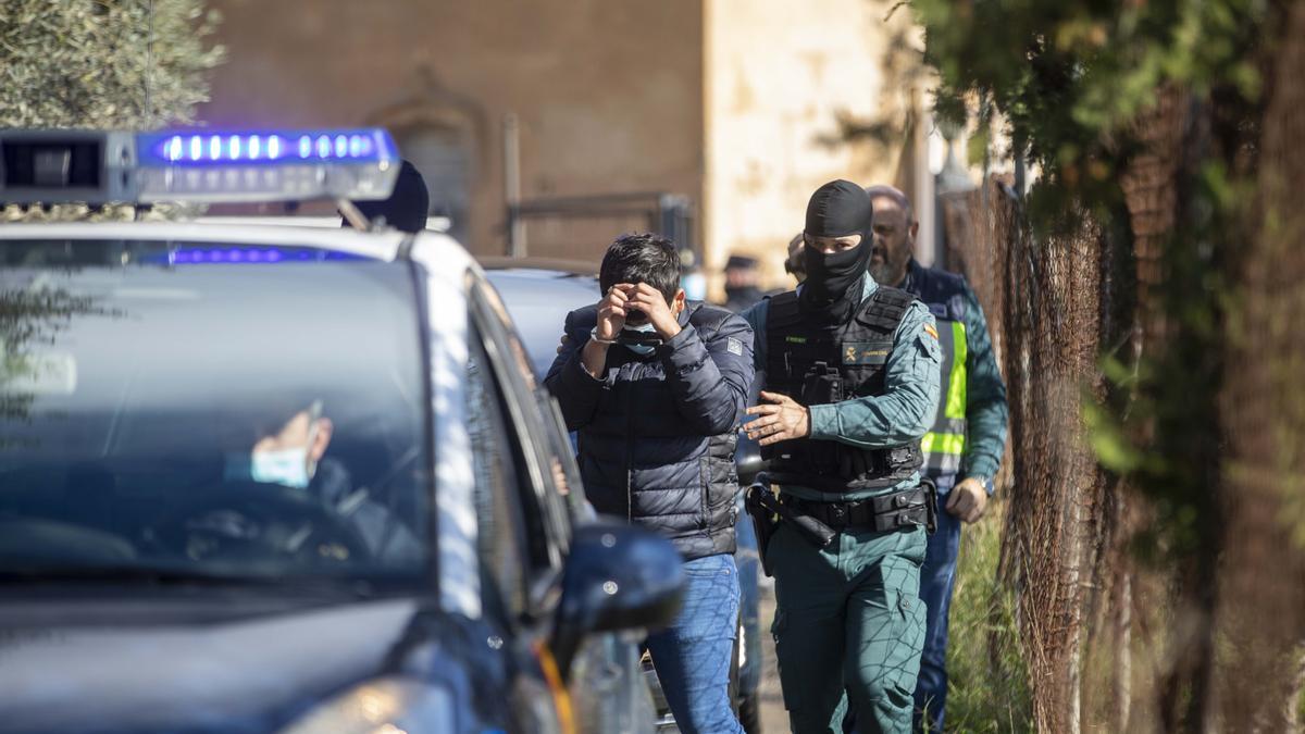 Un agente de la guardia civil introduce a un detenido en un coche patrulla.