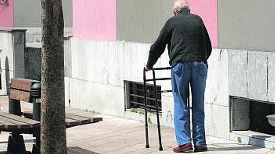 Un hombre pasea por Mieres con ayuda de un andador.