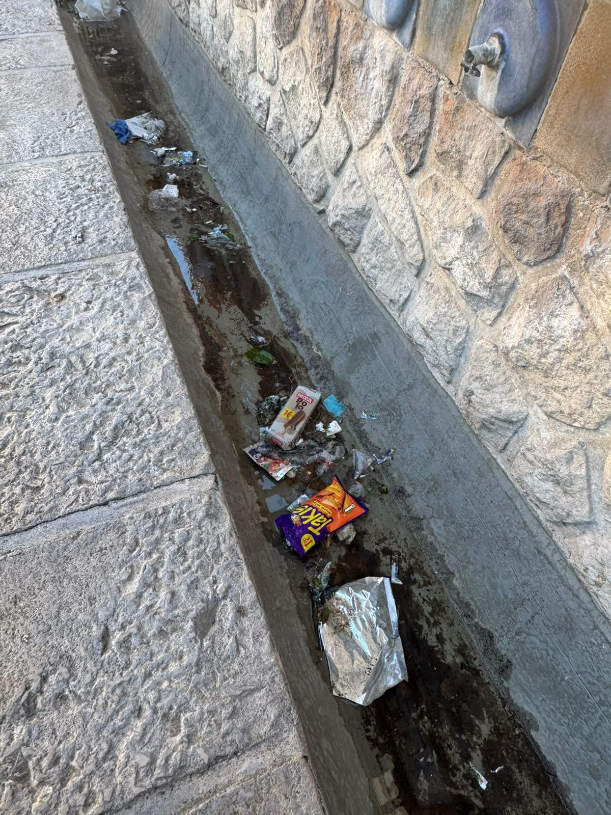 Basura acumulada en una canaleta de la plaza.
