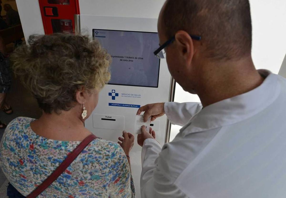 Un sanitario ayuda a una paciente a utilizar la máquina de citaciones del Álvarez-Buylla.