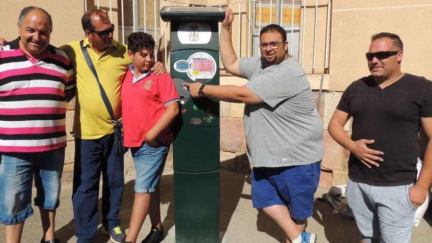 Un vendedor, junto a otras personas, señala la máquina expendedora.