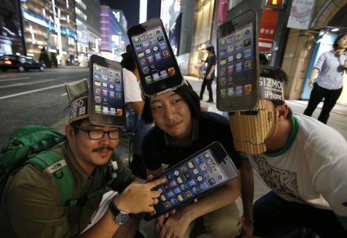 Men wearing cardboard hats, depicting Apple's new iPhone 5, pose for photos as they wait for the release of the phone near Apple Store Ginza in Tokyo