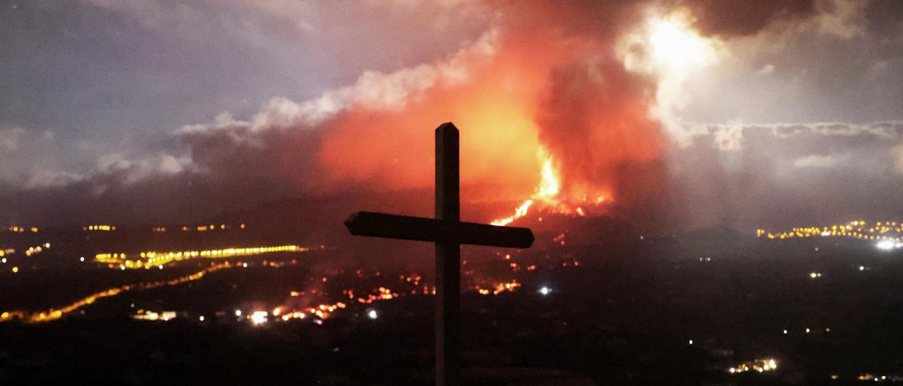 A cross is seen as lava and smoke rise following the eruption of a volcano on the Island of La Palma