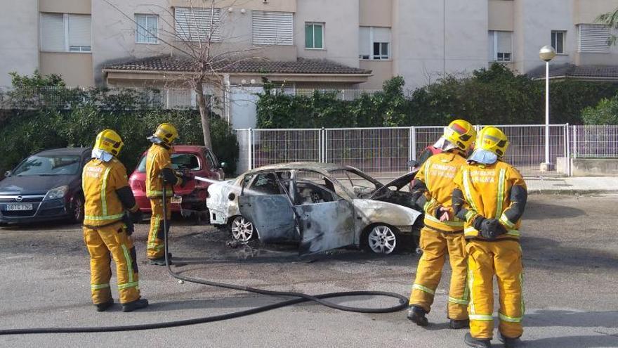 Varios bomberos, junto al coche incendiado