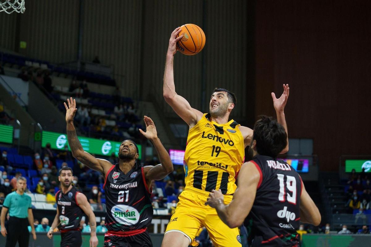 El pívot del Lenovo Tenerife Giorgi Shermadini (2-d) entra a canasta ante Burak Yildizli (d) y Tony Taylor, ambos del Pinar Karsiyaka, durante un partido de la Liga de Campeones de baloncesto, en una fotografía de archivo. EFE/Ramón de la Rocha