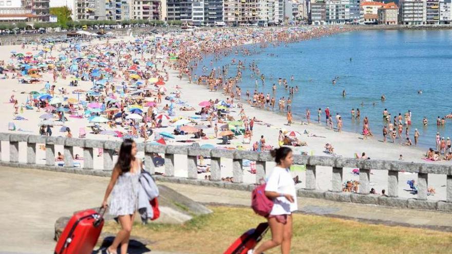 Dos turistas se dirigen a un hotel ante la playa de Silgar. // G. Santos