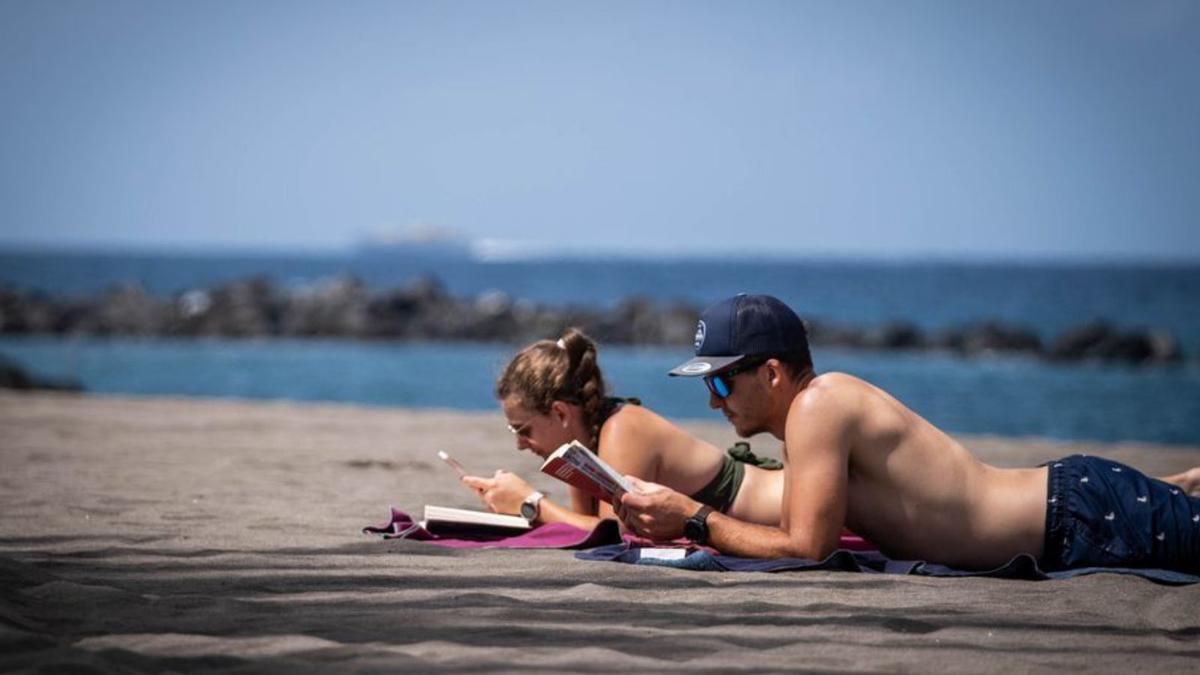 Dos turistas toman sol en una playa de Adeje. | ANDRÉS GUTIÉRRREZ