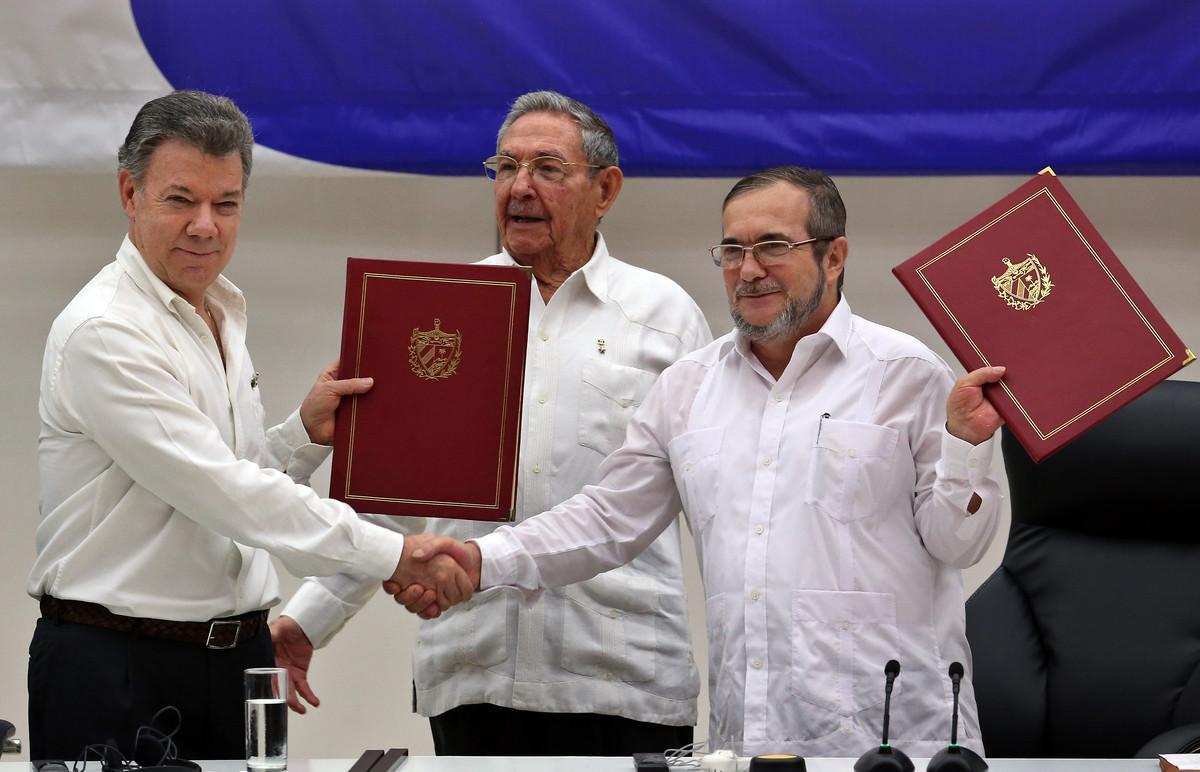 HAB01. LA HABANA (CUBA), 23/06/2016.- El delegado de las FARC en Cuba, Rodrigo Londoño Echeverri, alias Timochenko (d) y el presidente de Colombia, Juan Manuel Santos (i) junto a el presidente de Cuba, Raúl Castro (c) sostienen en sus manos el acuerdo de paz entre el Gobierno colombiano y las FARC, durante la ceremonia en La Habana (Cuba) hoy, jueves 23 de junio de 2016, del acuerdo para el cese al fuego en Colombia. El acto para oficializar el acuerdo de cese al fuego bilateral y definitivo en Colombia comenzó hoy en La Habana, encabezado por el presidente Juan Manuel Santos y por Timochenko, máximo líder de las FARC, y con la asistencia de seis presidentes de la región y el secretario general de la ONU. EFE/ALEJANDRO ERNESTO