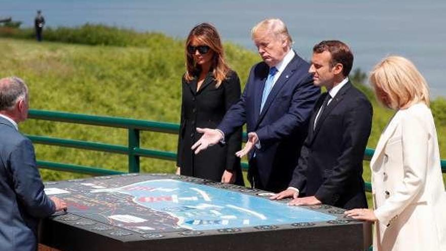 Trump contempla un mapa del desembarco, en presencia de Macron y sus respectivas esposas, en Colleville-sur-Mer (Normandía). // Efe