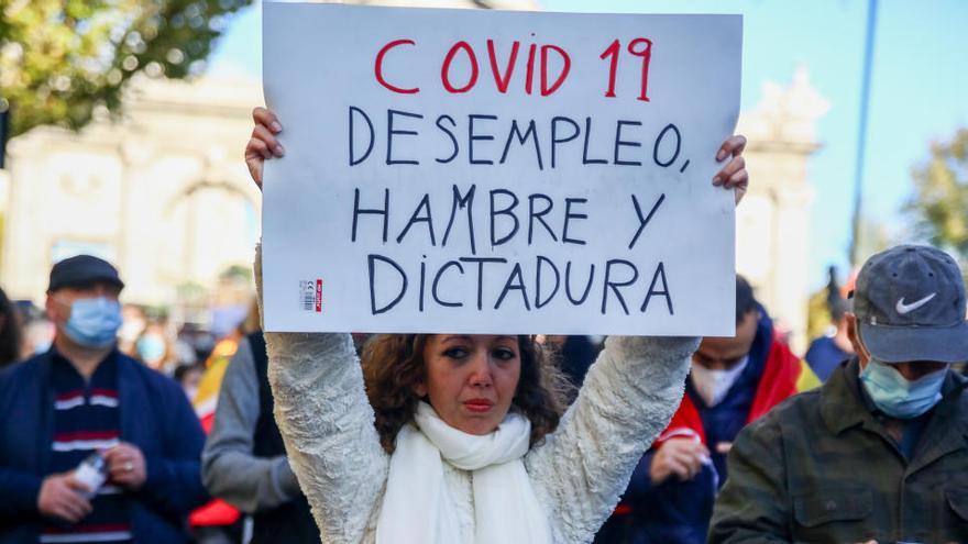 Una mujer sostiene una pancarta donde se puede leer &quot;Covid19 desempleo, hambre y dictadura&quot;