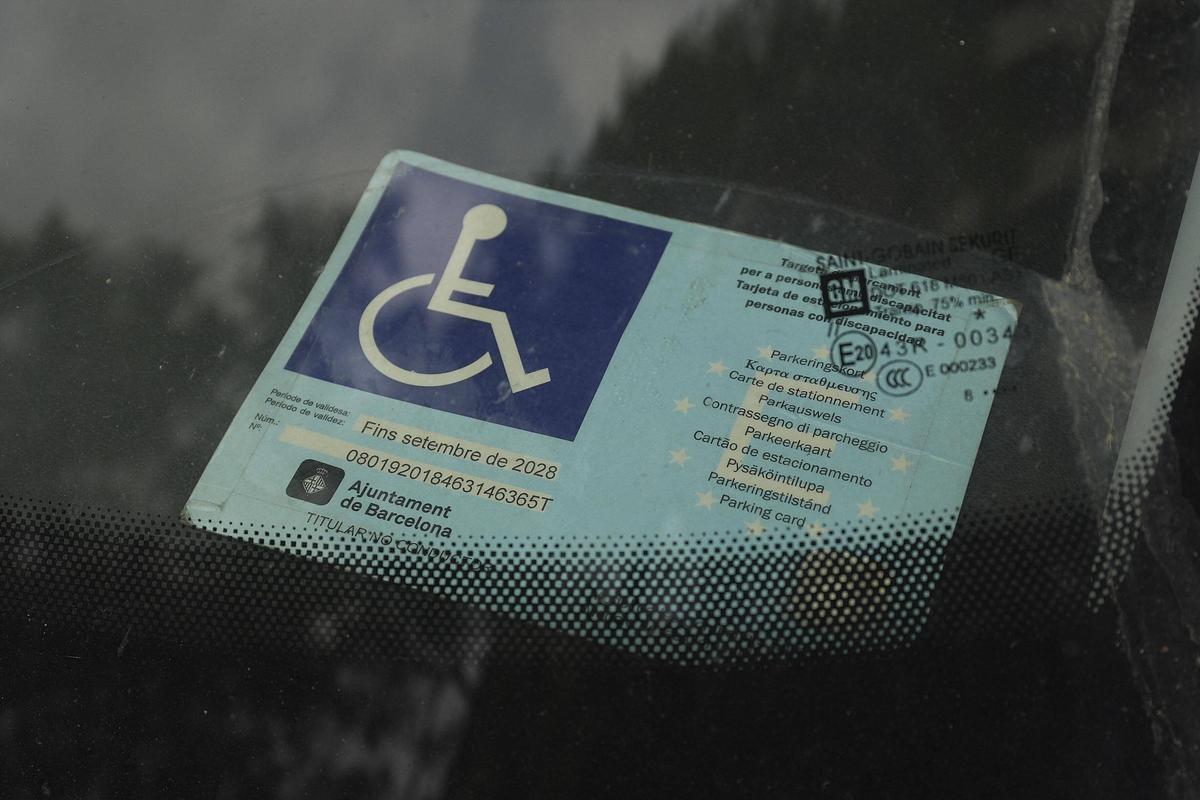 Una targeta de mobilitat reduïda d'un cotxe estacionat a Girona.
