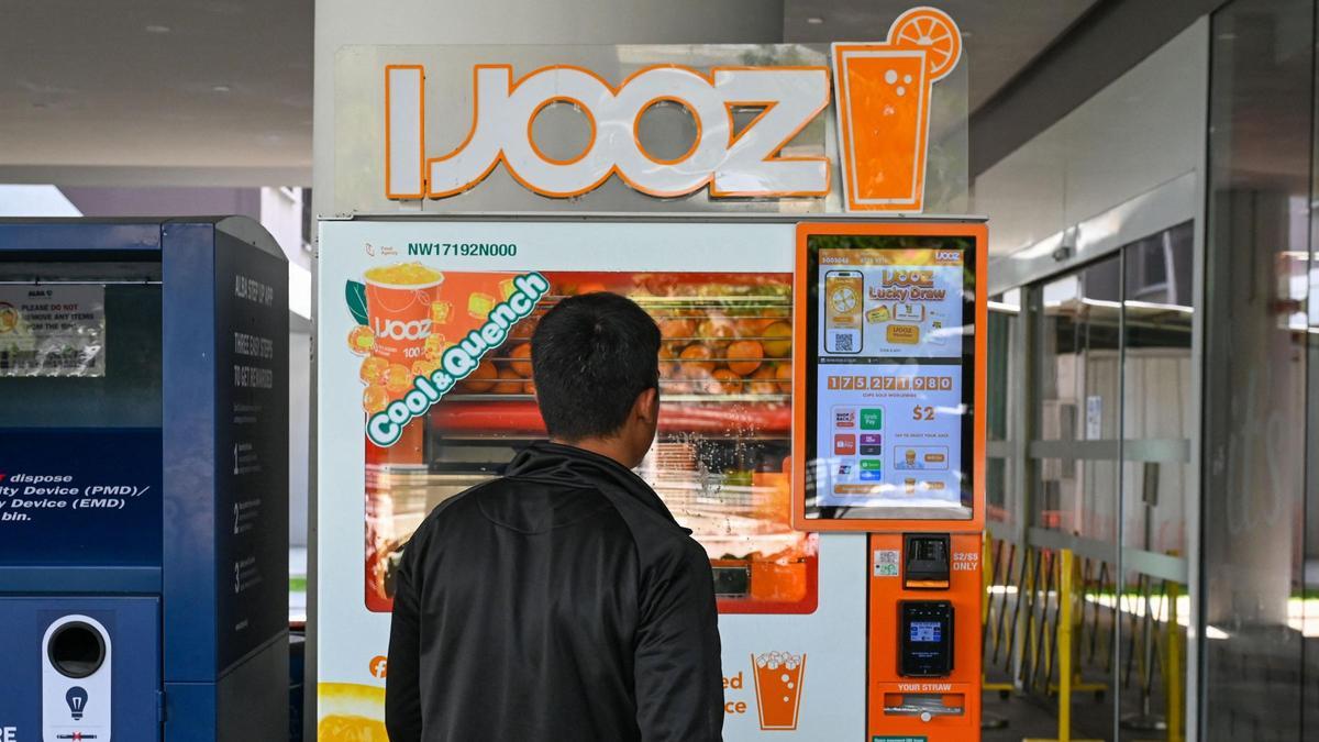 Un hombre se encuentra frente a una máquina expendedora de zumo de naranja a las puertas de un centro comercial en Singapur