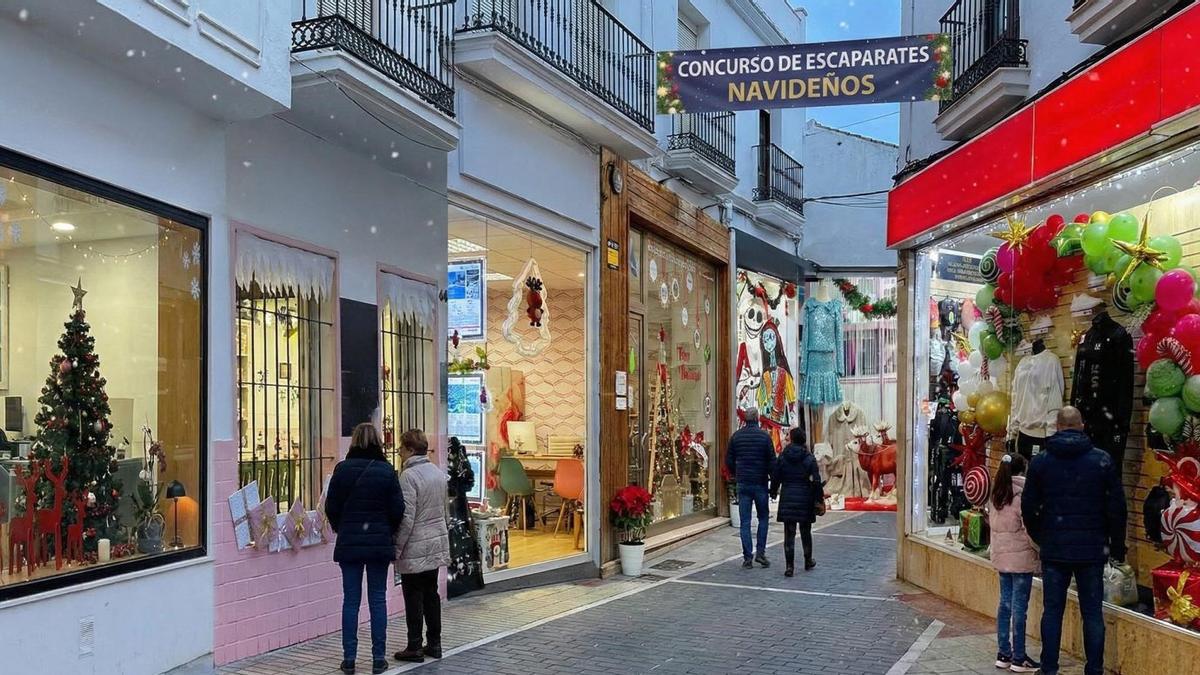 Vecinos de San Pedro observan los escaparates de comercios que participan en un concurso de decoración.