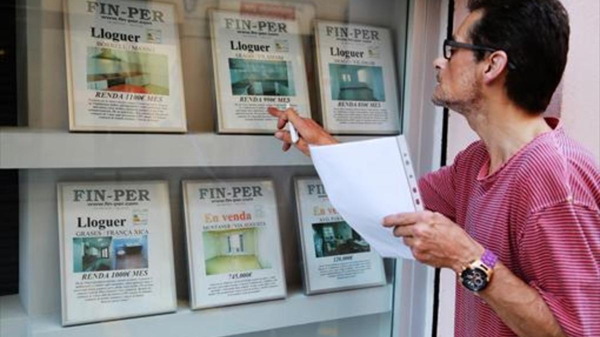 Anuncios de pisos en alquiler en el escaparate de una inmobiliaria.