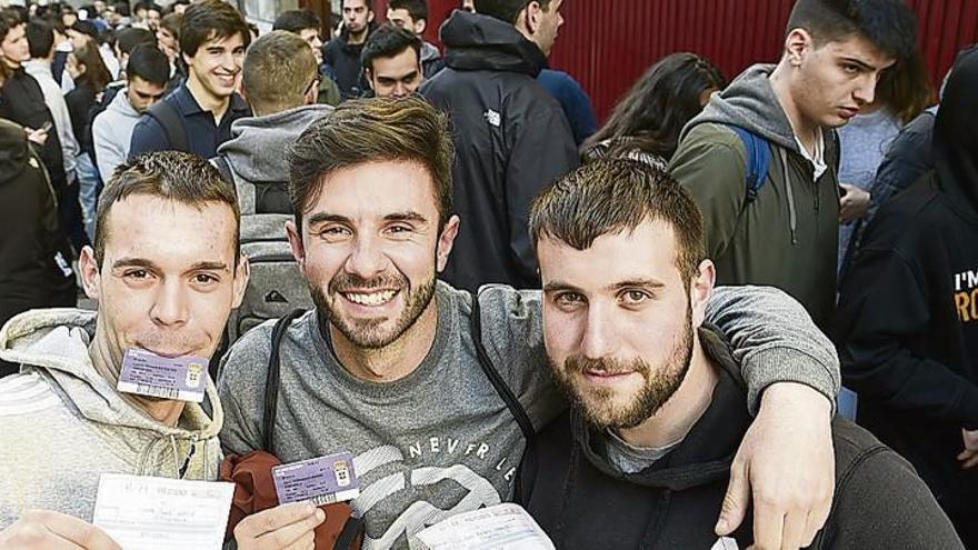 Tres aficionados del Oviedo, ayer, con sus entradas ante la cola para comprar las localidades.