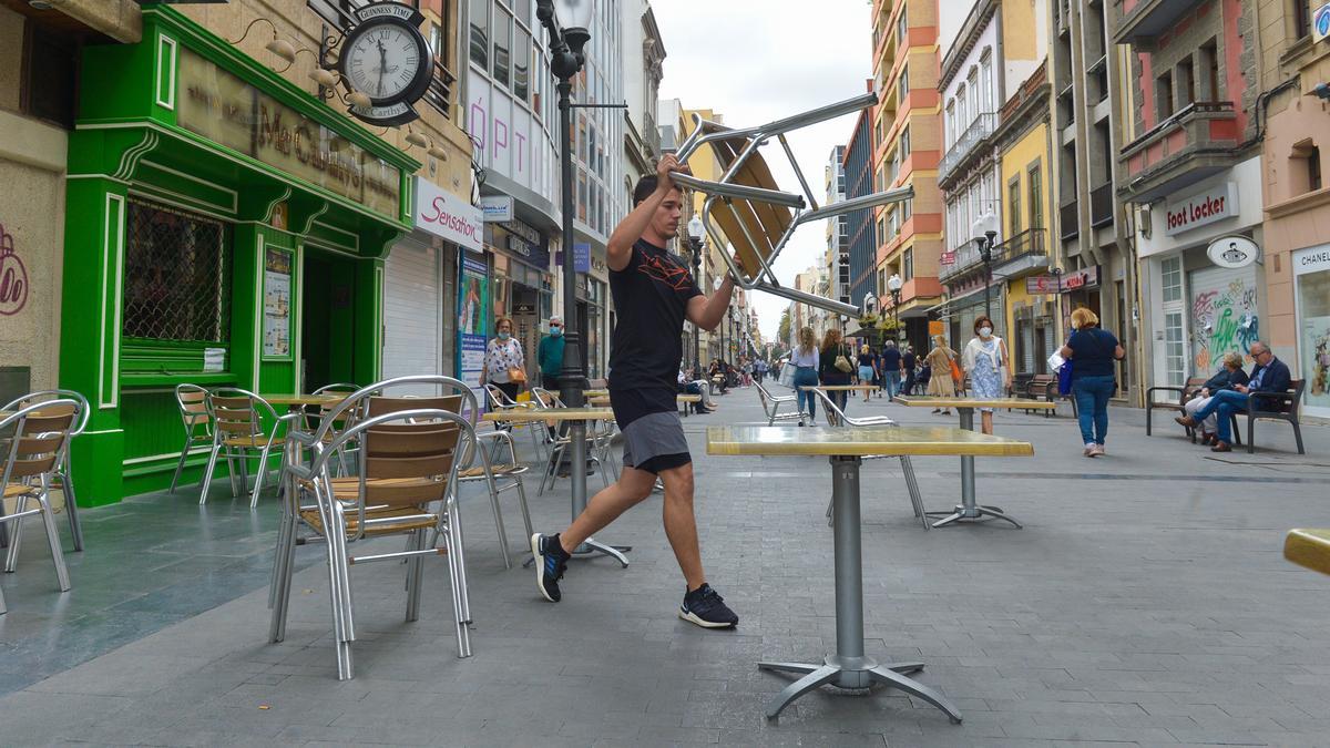 Un trabajador monta las mesas en una terraza.