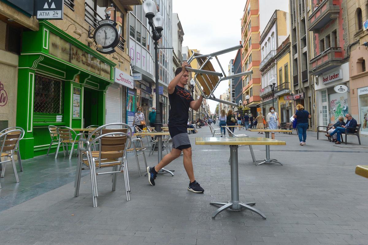 Un trabajador monta las mesas en una terraza.