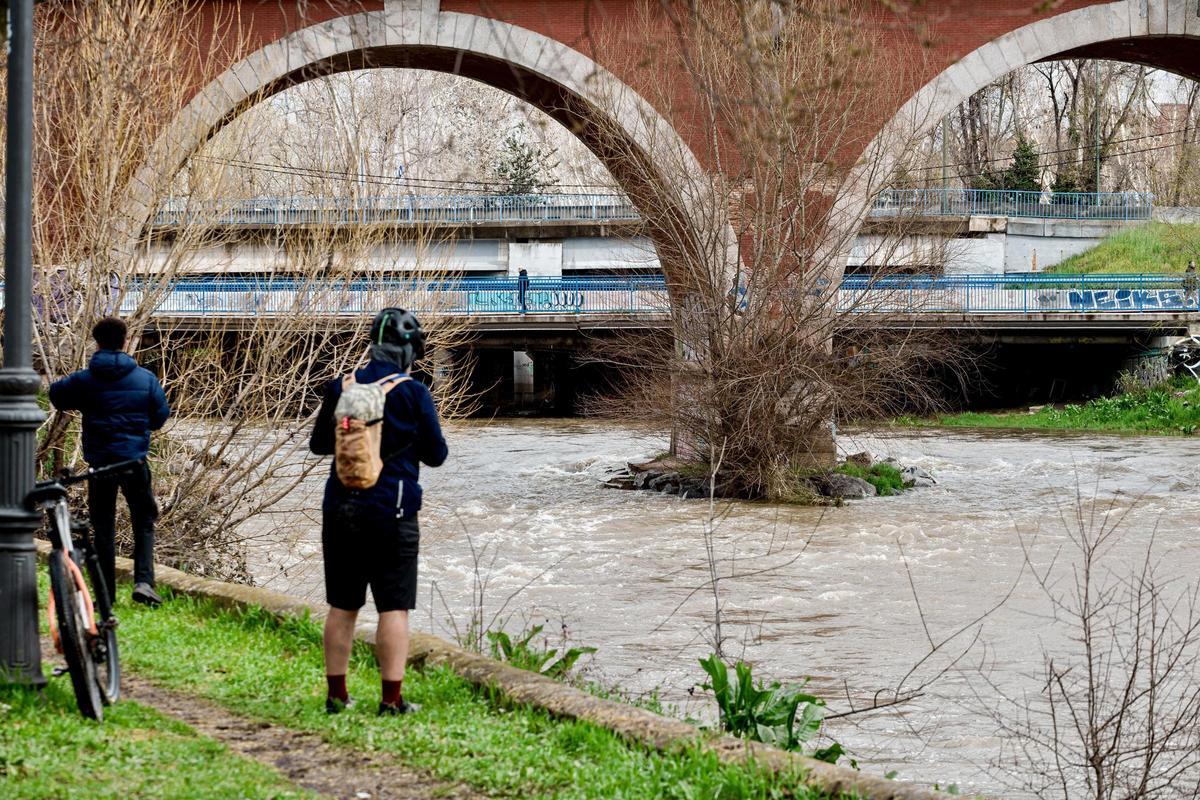 Dos personas observan el río Manzanares a su paso por el puente de los Franceses.
