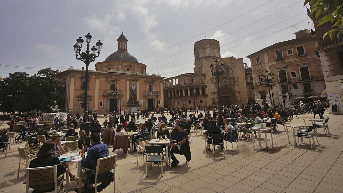 Panorámica del aspecto de la plaza de la Virgen de València ayer, con las terrazas de hostelería llenas de clientes. | EDUARDO RIPOLL