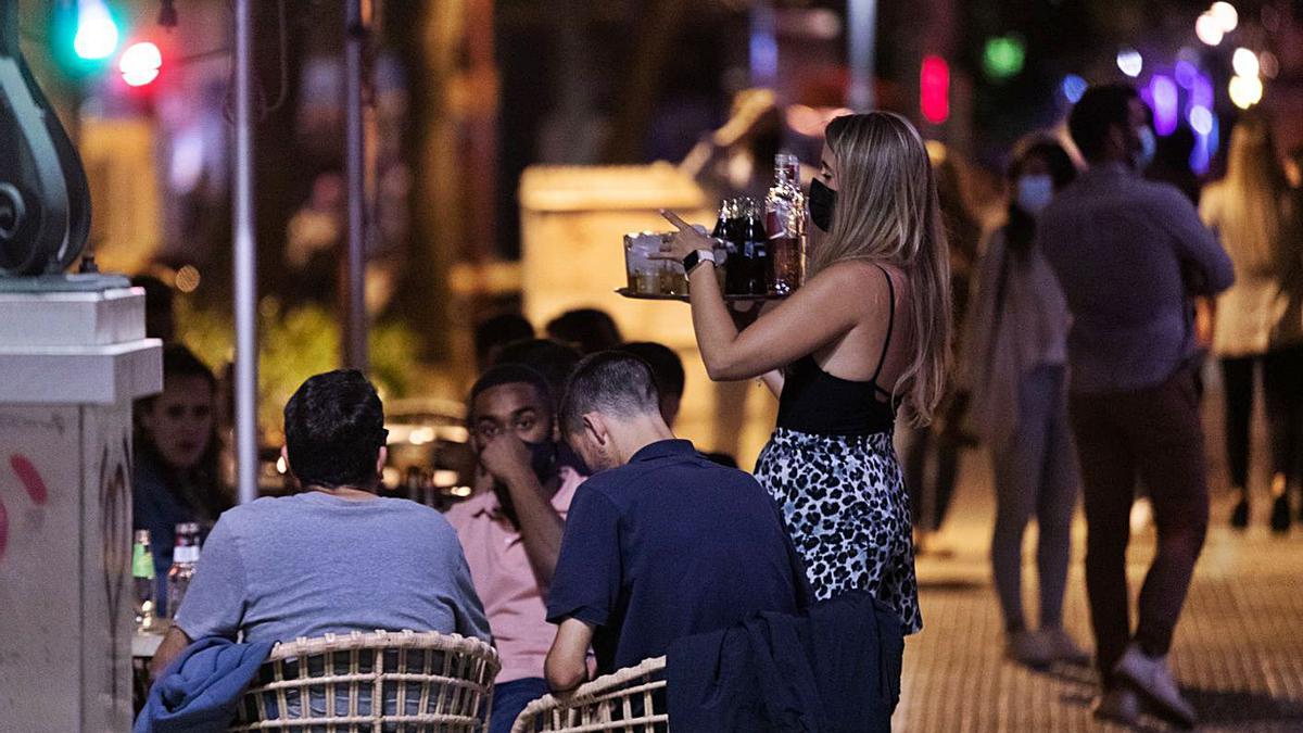 Una cambrera serveix clients en una terrassa d’un establiment d’oci nocturn