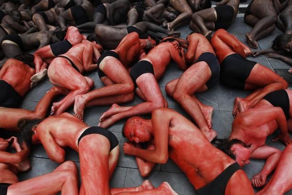 Animal {rights} {protesters} {lie} {covered} in {fake} blood and black {paint} as {they} {form} the {shape} of a bull {during} a {demonstration} in Pamplona