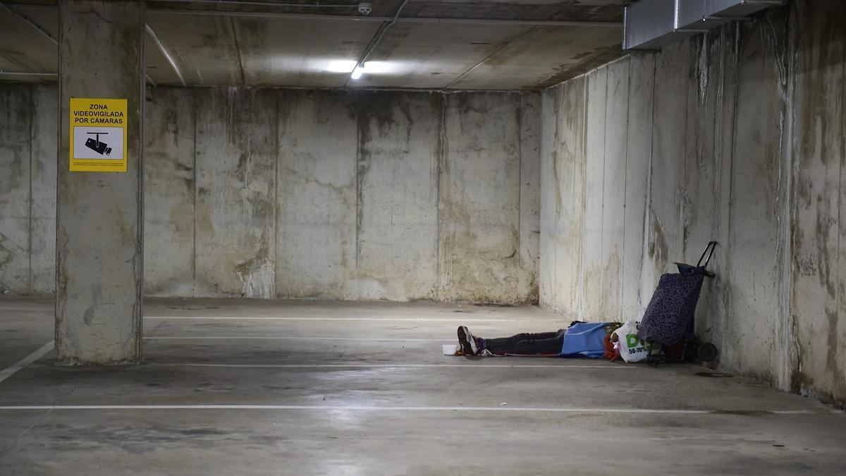 Una persona sin hogar, durmiendo en el parking rotatorio de Plasencia.
