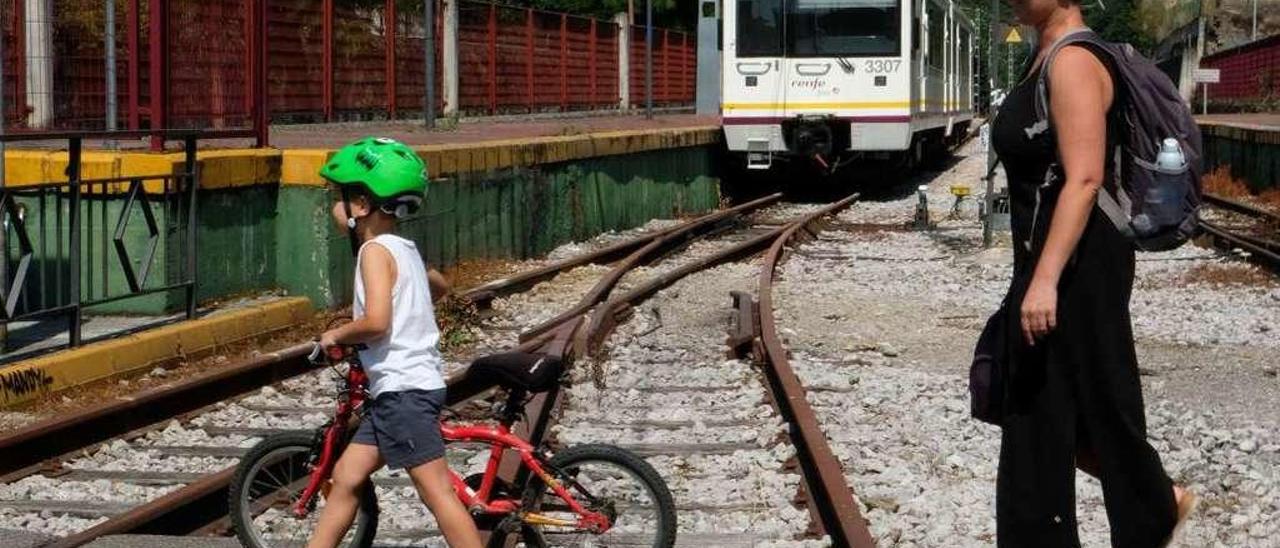 Enzo Martínez y Angélica García cruzan las vías del tren en la estación de Pola de Laviana.