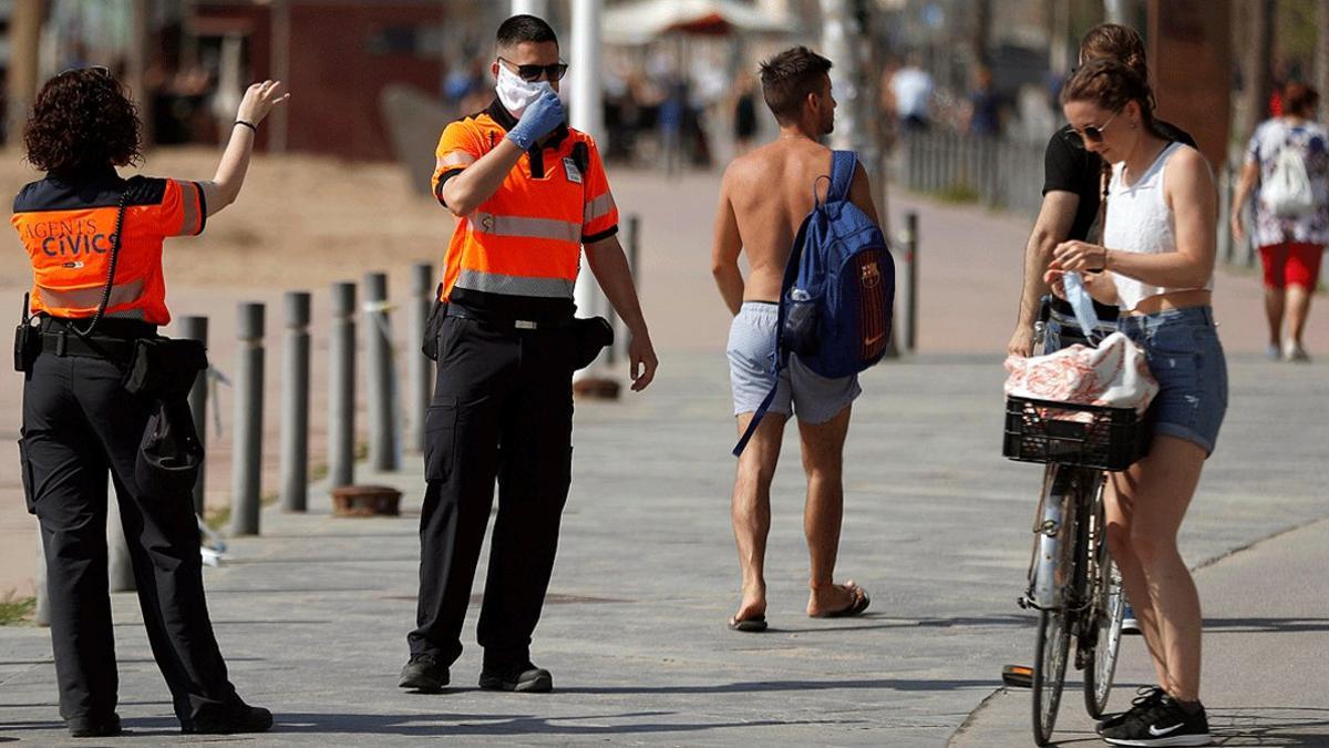 Agentes cívicos de Barcelona informan a una joven de la obligatoriedad de llevar mascarilla, el pasado 30 de mayo