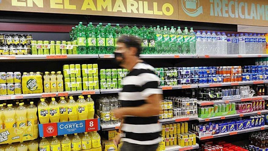 Un client passa per davant del lineal de refrescos on s&#039;observa un cartell que explica on dipositar aquests envasos |