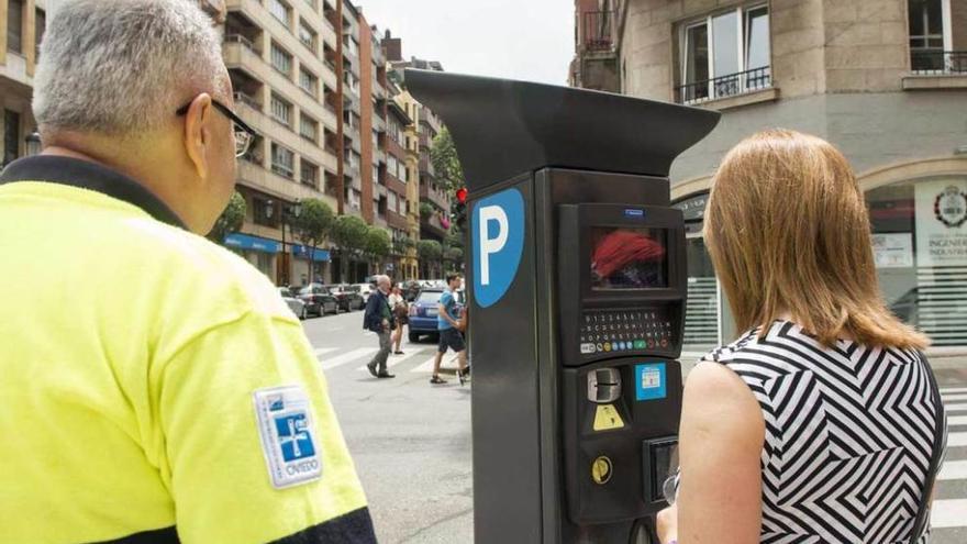 Un controlador de la ORA y una usuaria, ante un parquímetro.