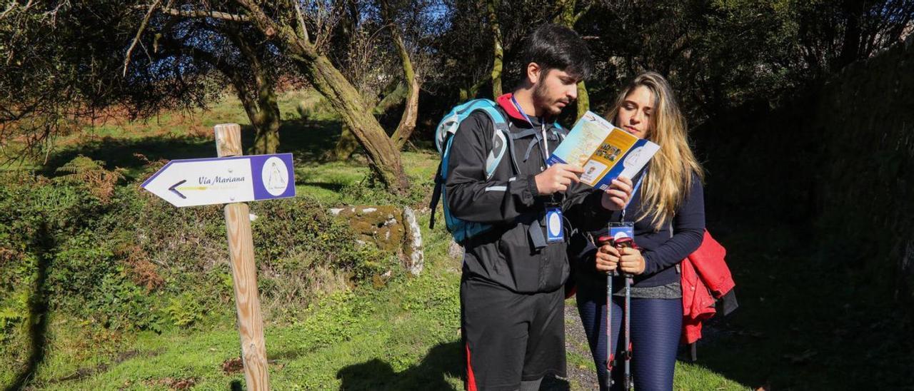 Dos peregrinos junto a un indicador de la Vía Mariana.  // Anxo Gutiérrez